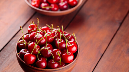 Ripe cherries in a clay bowl. Red cherries on a wooden table. Healthy vegan food concept. Top view. Copy space