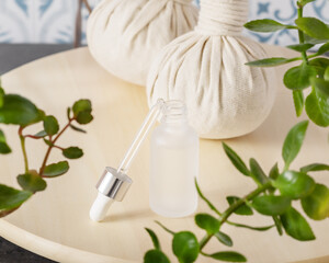 Wellness composition with white glass dropper bottle with white lid on a wooden shelf with spa accessories and home plants. Beauty salon mockup. Hand made cosmetics and glow serum. Soft focus stile