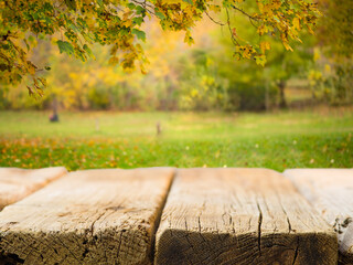 Naklejka na ściany i meble Empty wooden table on the background of beautiful autumn nature. Picnic, outdoor recreation, calm scenes, vacation, day off, romance, solitude, beauty of nature. There is free space to insert.