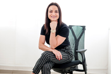 Uma bela mulher empreendedora sorridente sentada em uma cadeira de escritório com uma mão no...