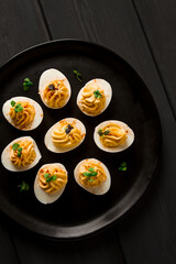 Boiled eggs stuffed with yolk with mayonnaise, on a black plate, selective focus, blurry, close-up, no people,