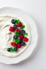 Breakfast, yogurt with fresh berries, raspberries and blueberries, on a white background, selective focus, no people, healthy food,