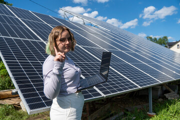A young female engineer working with solar panels programs and optimizing work of the solar...