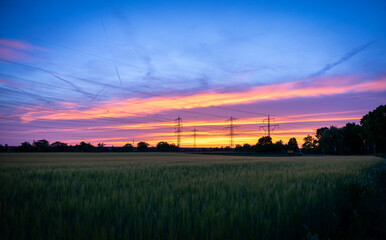 a beautiful atmospheric red sunset on a field with power poles