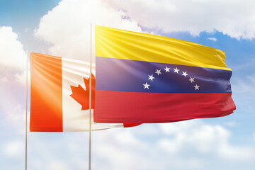 Sunny blue sky and flags of venezuela and canada