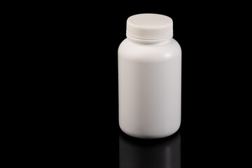 A white pill bottle. Jar of medicine. Photo taken on a black background.