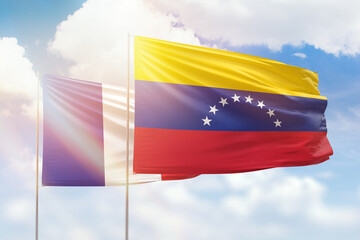 Sunny blue sky and flags of venezuela and france