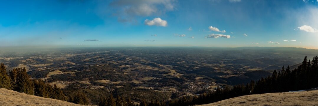 Aerial panorama view of Alpine hills in south of Styria from top of Schöckl peak near Graz with blue sky cloud on sunny winter day, Sankt Radegund, Austria