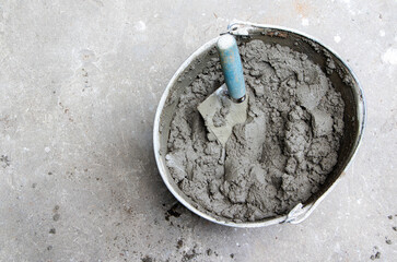 Mixing of concrete mortar.The builder prepares the cement mortar using a construction trowel.Plaster mortar in a bucket - obrazy, fototapety, plakaty