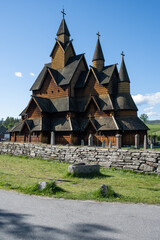Fototapeta na wymiar Heddal, Norway - May 26, 2022: Medieval graveyard and Heddal wooden stave church. Heddal Stavkirke, 13th century. Largest stave church in Norway. Sunny spring day. Selective focus