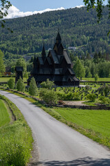 Heddal, Norway - May 26, 2022: Medieval graveyard and Heddal wooden stave church. Heddal Stavkirke, 13th century. Largest stave church in Norway. Sunny spring day.  Selective focus