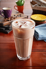 A glass of healthy fresh ICED LATTE isolated on wooden background side view