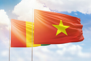 Sunny blue sky and flags of vietnam and guinea