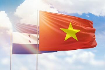Sunny blue sky and flags of vietnam and honduras