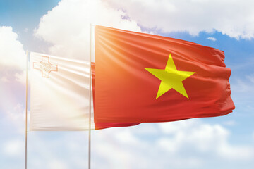 Sunny blue sky and flags of vietnam and malta