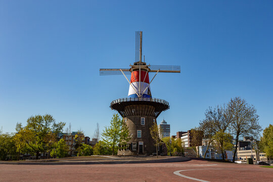 Historical Dutch windmill Molen de Valk with Dutch flag in Leiden, The Netherlands on a summer day with a bright blue sky