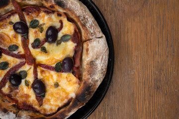 Pizza. Top view of a pizza with mozzarella cheese, grilled red bell peppers, ham, black olives and...