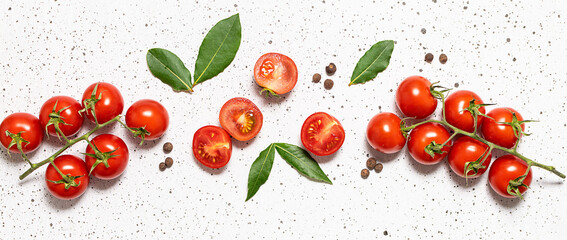 Ripe juicy cherry tomatoes with bay leaves and allspice on white marble background top view. 