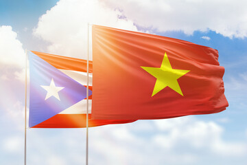 Sunny blue sky and flags of vietnam and puerto rico