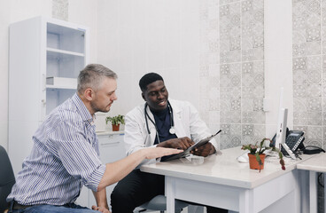 the patient and the doctor carefully study the results of the examination sitting at the table in...