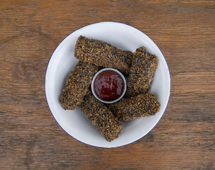 Vegan cuisine. Top view of vegan mozzarella sticks and quinoa with sweet chili dipping sauce in a white bowl on the wooden table. 