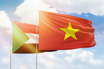 Sunny blue sky and flags of vietnam and sudan