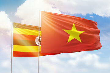 Sunny blue sky and flags of vietnam and uganda