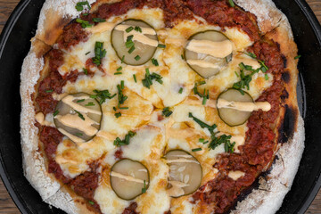 Colorful pizza background. Closeup view of a pizza with minced meat, tomato sauce, grilled cucumber, garlic aioli and chive, in the pizza pan.
