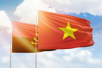 Sunny blue sky and flags of vietnam and angola