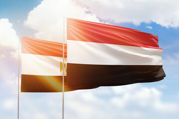 Sunny blue sky and flags of yemen and egypt