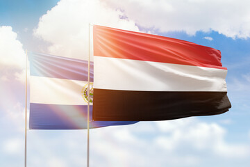 Sunny blue sky and flags of yemen and el salvador