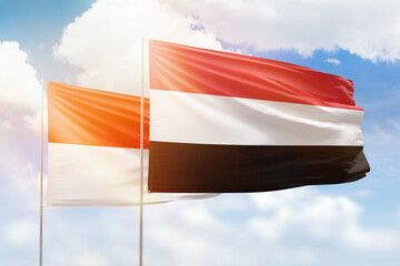 Sunny blue sky and flags of yemen and indonesia