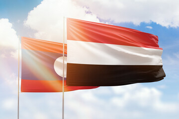 Sunny blue sky and flags of yemen and laos