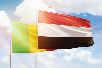 Sunny blue sky and flags of yemen and mali