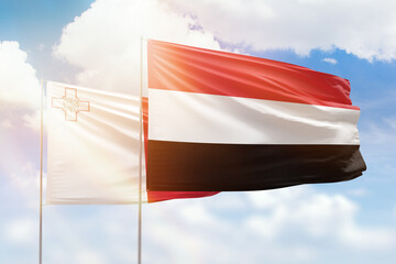 Sunny blue sky and flags of yemen and malta