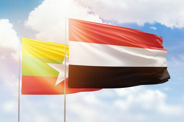 Sunny blue sky and flags of yemen and myanmar