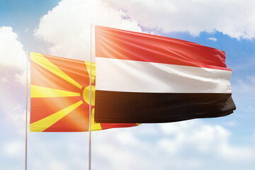 Sunny blue sky and flags of yemen and north macedonia
