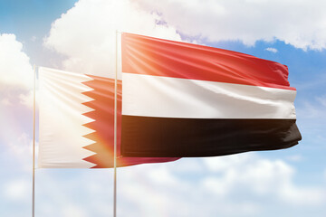 Sunny blue sky and flags of yemen and qatar