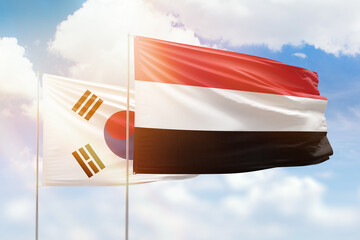 Sunny blue sky and flags of yemen and south korea