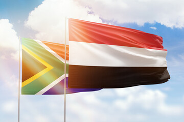Sunny blue sky and flags of yemen and south africa