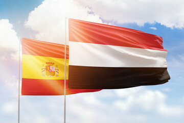 Sunny blue sky and flags of yemen and spain