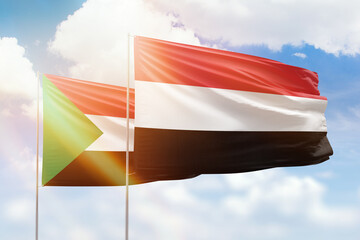 Sunny blue sky and flags of yemen and sudan