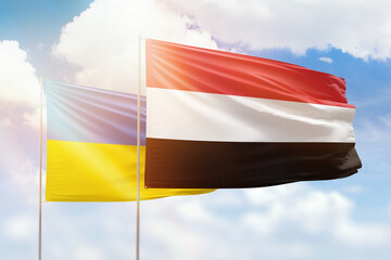 Sunny blue sky and flags of yemen and ukraine