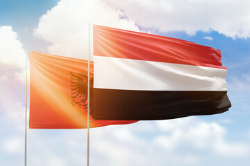 Sunny blue sky and flags of yemen and albania