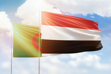 Sunny blue sky and flags of yemen and algeria
