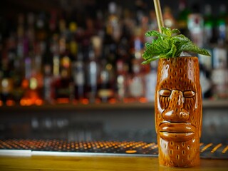 Delicious Tiki cocktail in trendy bar with bottle out of focus background and copy space vertical...