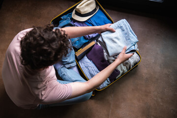 young and modern woman packing suitcase, preparing for vacation and spending time at home