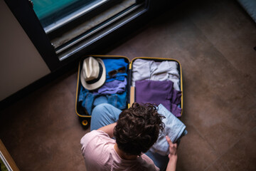 young and modern woman packing suitcase, preparing for vacation and spending time at home