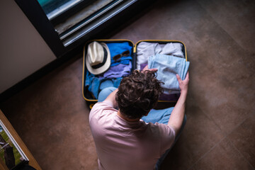 young and modern woman packing suitcase, preparing for vacation and spending time at home