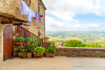 A medieval stone building with laundry hanging overlooking the hills and countryside of Tuscany in the hill town of Volterra, Italy. - obrazy, fototapety, plakaty